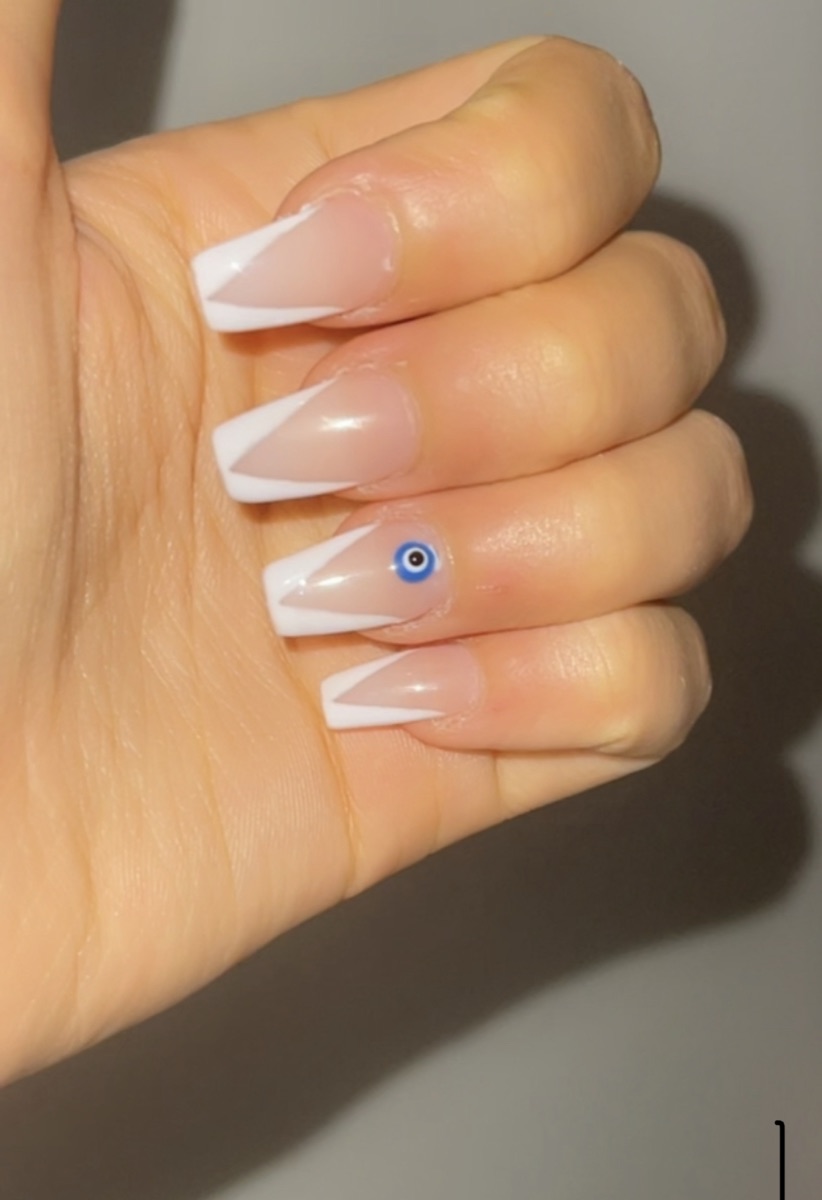 White French tip nails with a blue evil-eye accent